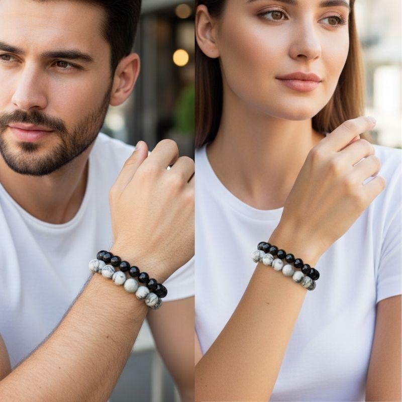 Two people wearing black and white beaded bracelets on a blurred background