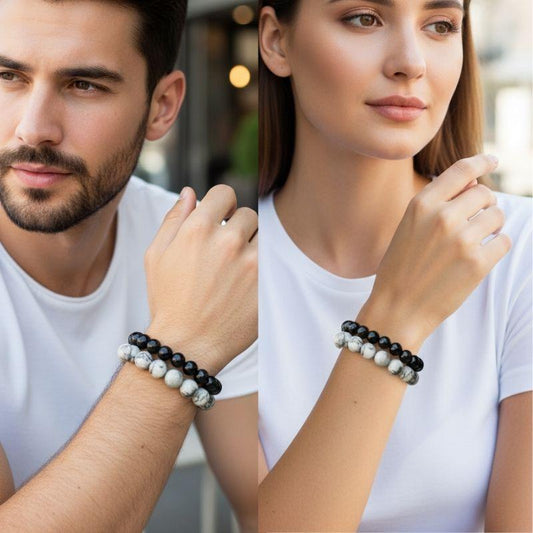 Two people wearing black and white beaded bracelets on a blurred background